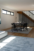Open plan living with dining table on Pebbles Light Grey Rug by Four Corners Rugs and living room with Plush Ice Blue Rug by Four Corners Rugs