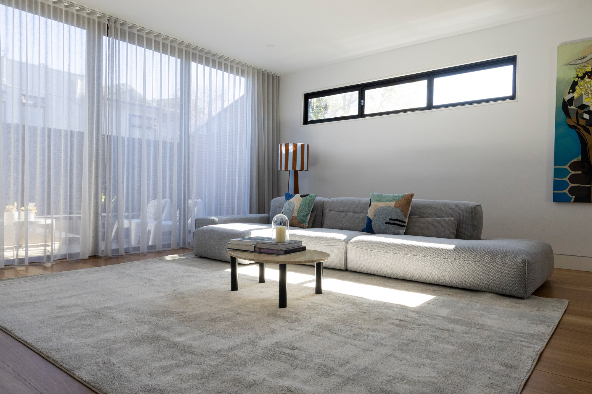 Modern living room with a grey sofa, coffee table, and large windows on Plush Light Grey Rug by Four Corners Rugs