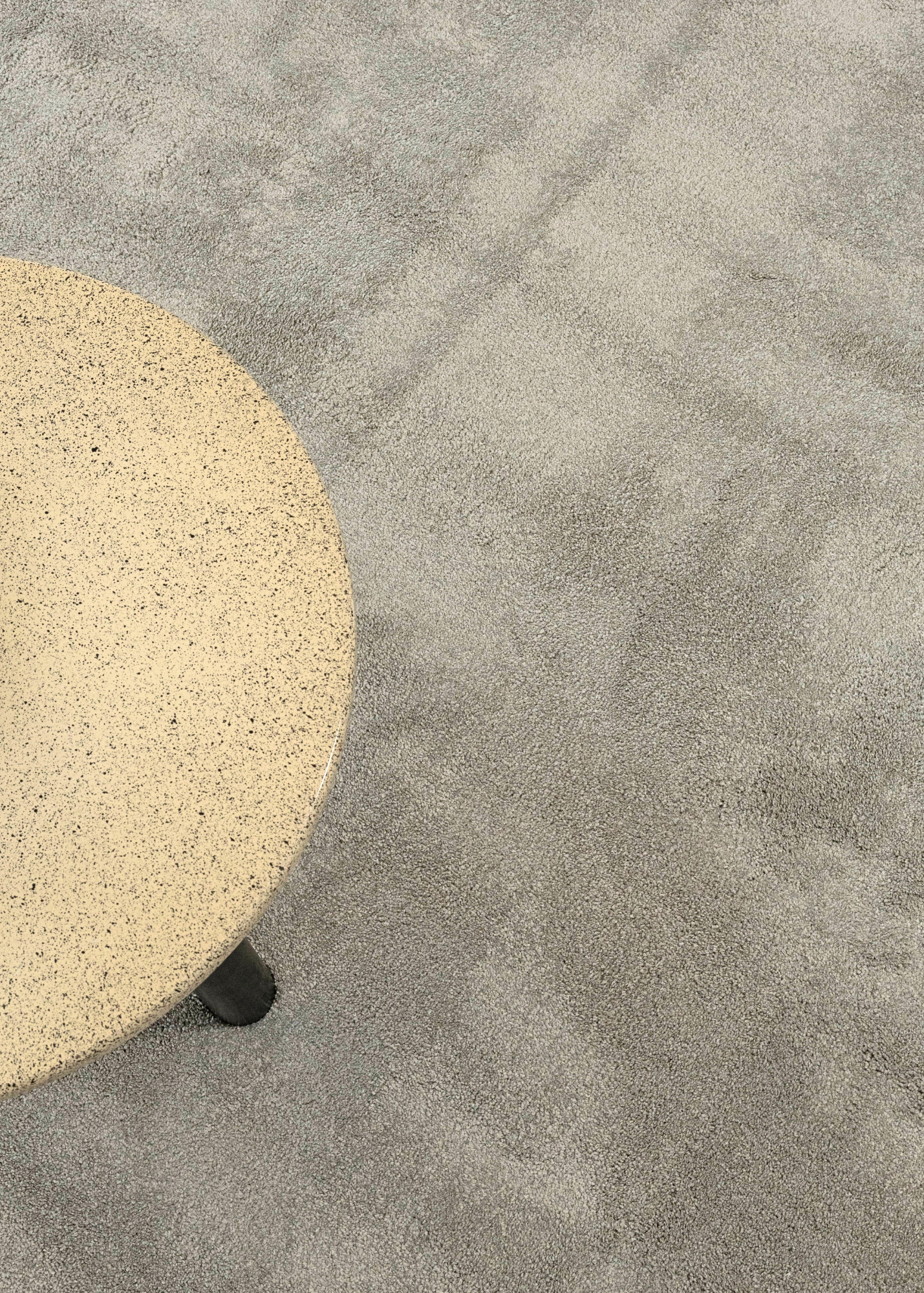 Round beige stone table on Plush Light Grey Rug by Four Corners Rugs