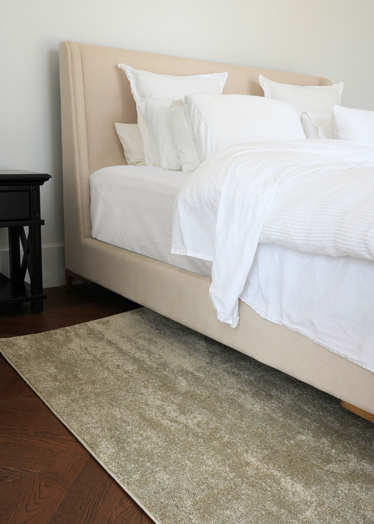 Beige bed with white bedding in a bedroom setting with Plush Olive Green Rug by Four Corners Rugs