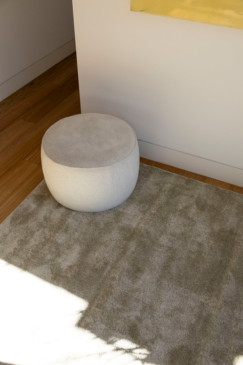 Round grey ottoman on Plush Olive Green Rug by Four Corners Rugs