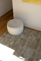 Round grey ottoman on Plush Olive Green Rug by Four Corners Rugs