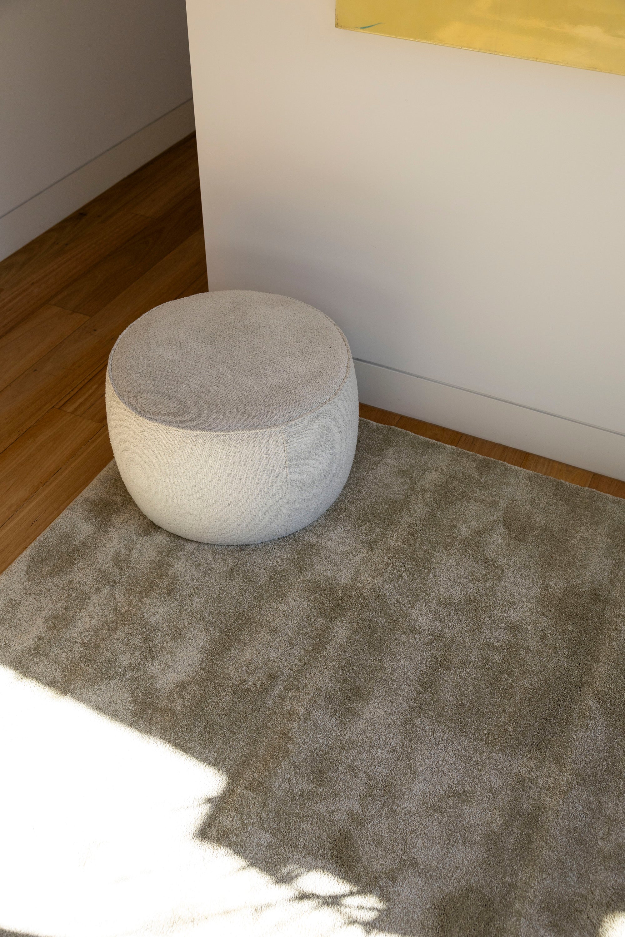 Round grey ottoman on Plush Olive Green Rug by Four Corners Rugs