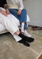 Two people sitting on a bed with Plush Olive Green rug by Four Corners Rugs under their feet