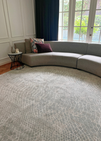 Grey sectional sofa with decorative pillows in a room with large windows on Python Blue Base Rug