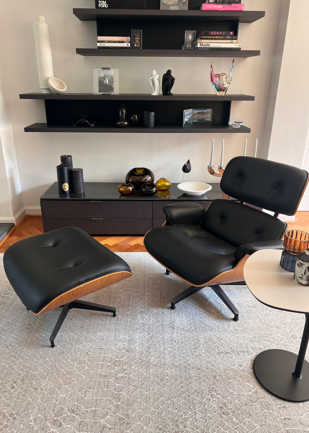 Modern black lounge chair and ottoman in a living room with shelves and Python Natural Base Rug by Four Corners Rugs