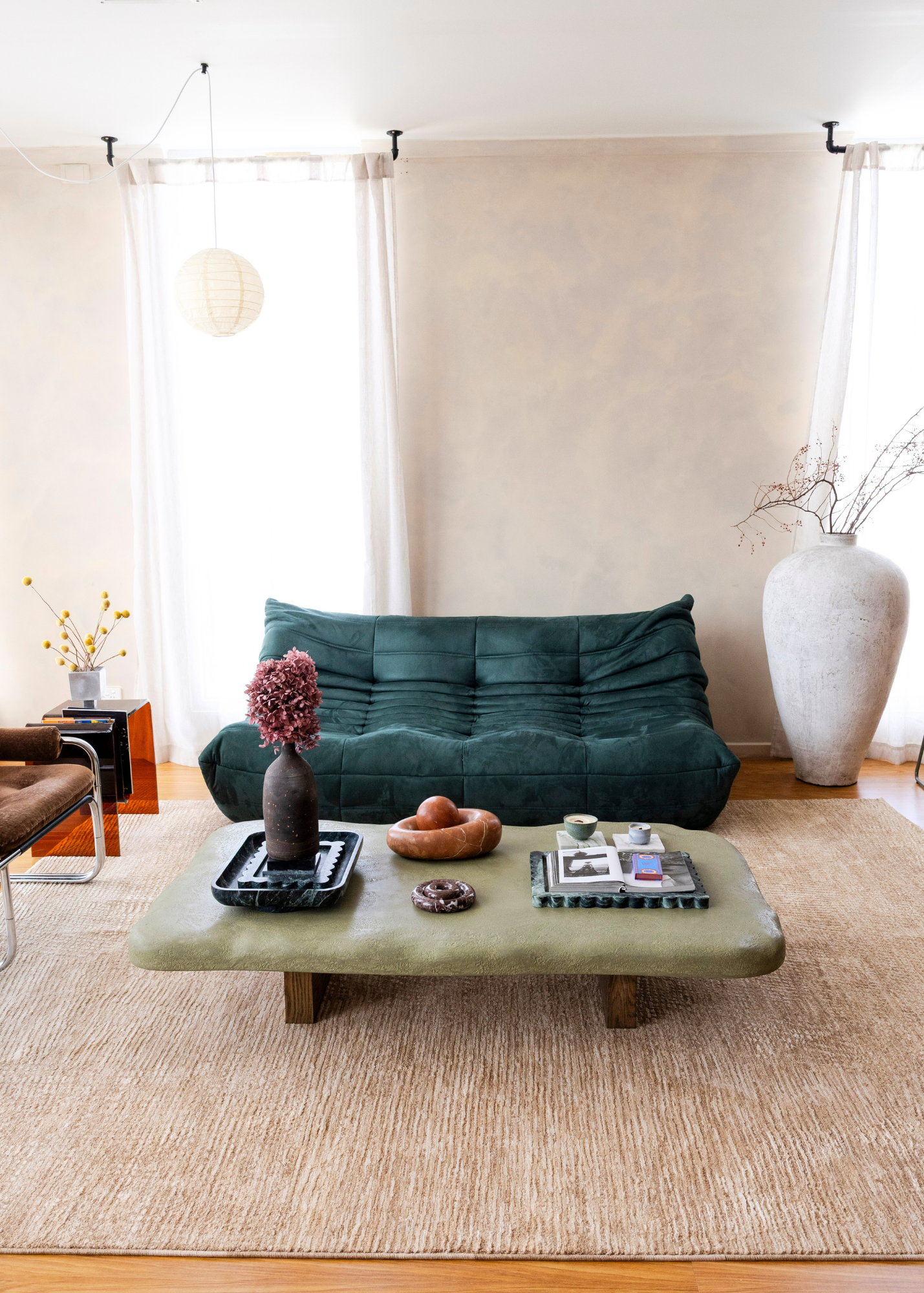 Modern living room with a green sofa, coffee table, and decorative items on Trinity Biscuit Rug by Four Corners Rugs