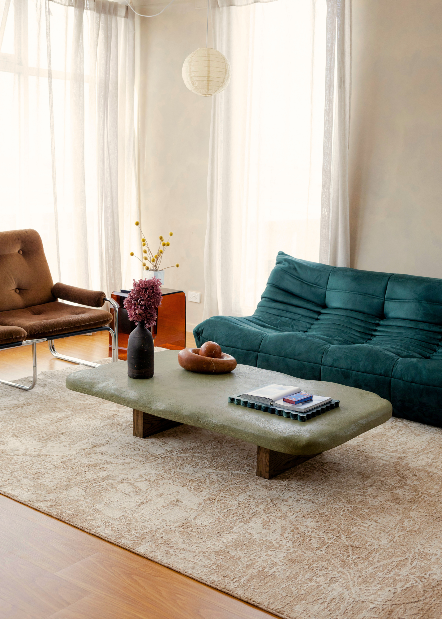 Modern living room with a teal sofa, brown armchair, a coffee table and Trinity Floral Biscuit Rug by Four Corners Rugs