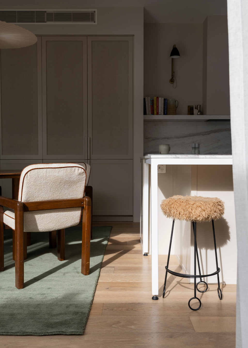 Chair and stool in a room with neutral decor with Wool Texture Green Rug
