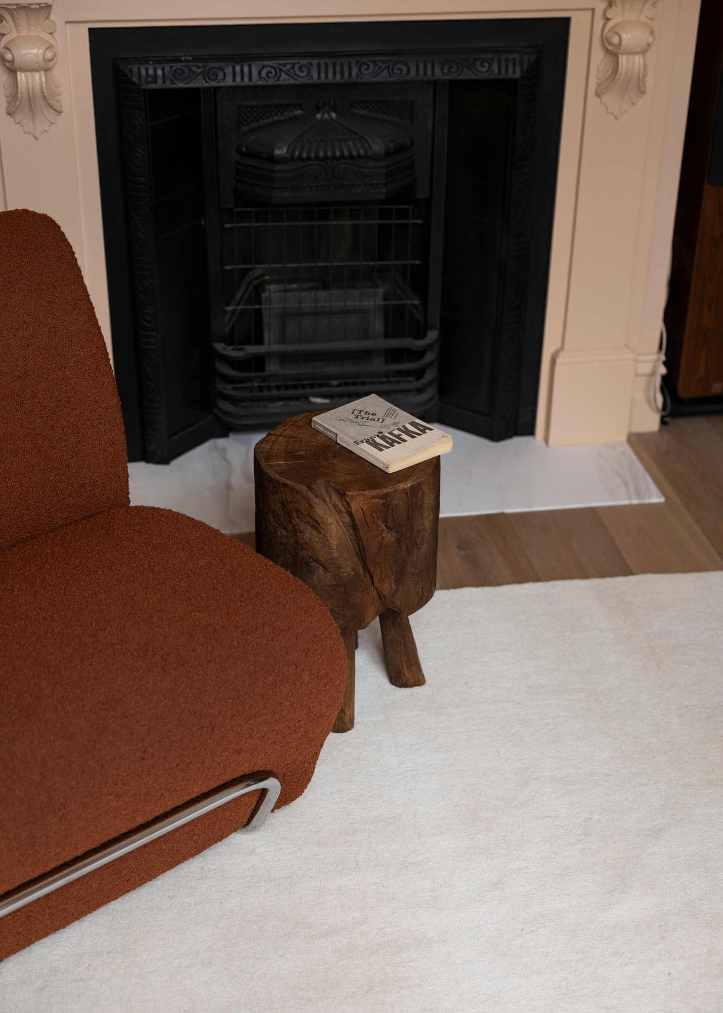 Burnt orange armchair next to a wooden stool with Wool Texture Milk Cream Rug