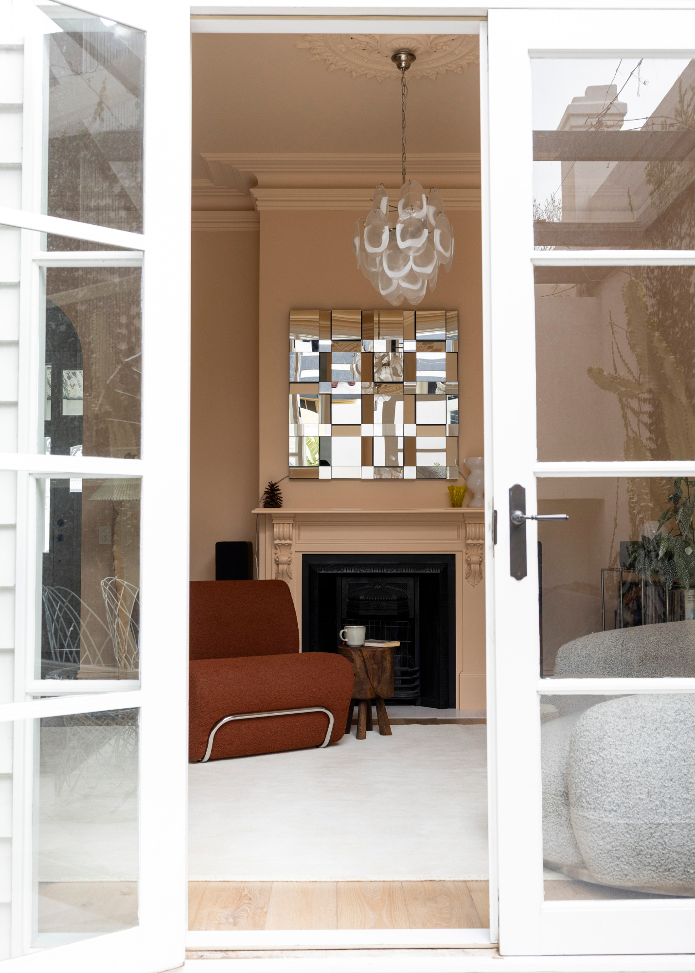Living room with a fireplace, mirror, and sofa viewed through a glass door on Wool Texture Milk Cream Rug