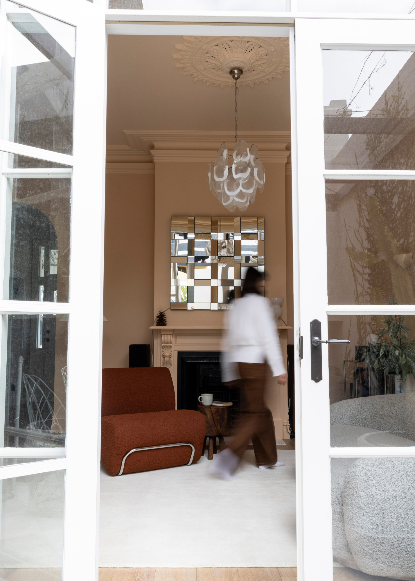 Living room with a chandelier, mirror, and person walking by on Wool Texture Milk Cream Rug
