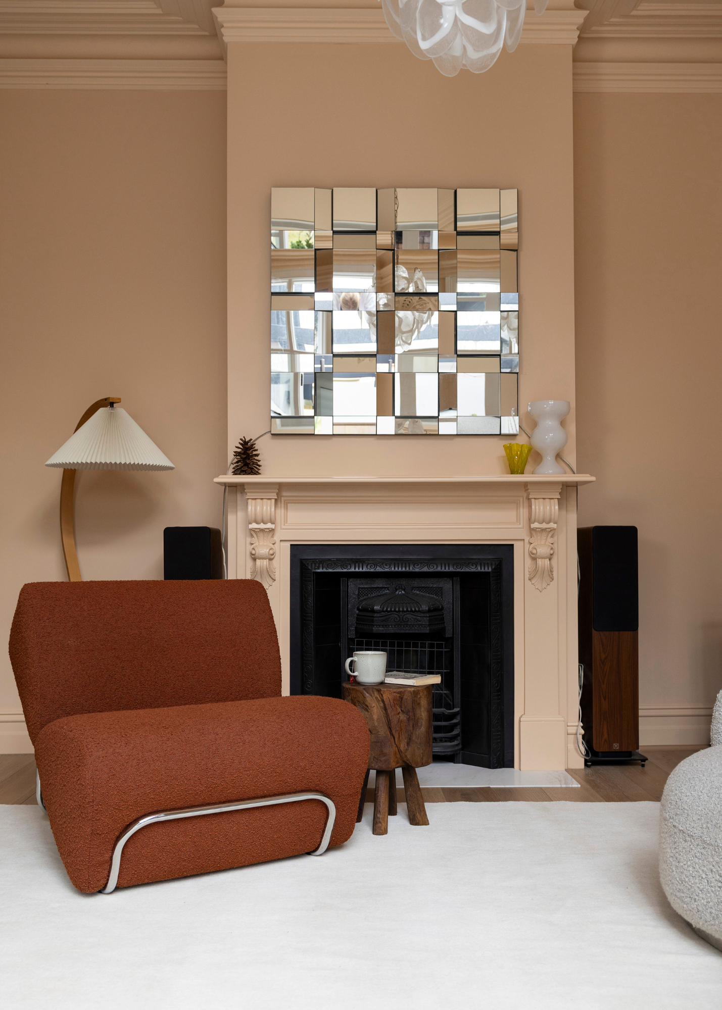 Living room with a burnt orange armchair, fireplace, and decorative mirror on Wool Texture Milk Cream Rug