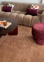 Living room with a brown sofa, burgundy ottoman, and coffee table on Wool Texture Teddy Brown Rug by Four Corners Rugs 
