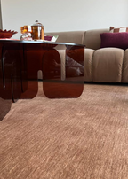 Living room with a burgundy glass coffee table, sofa, and decorative items on Wool Texture Teddy Brown Rug by Four Corners Rugs 