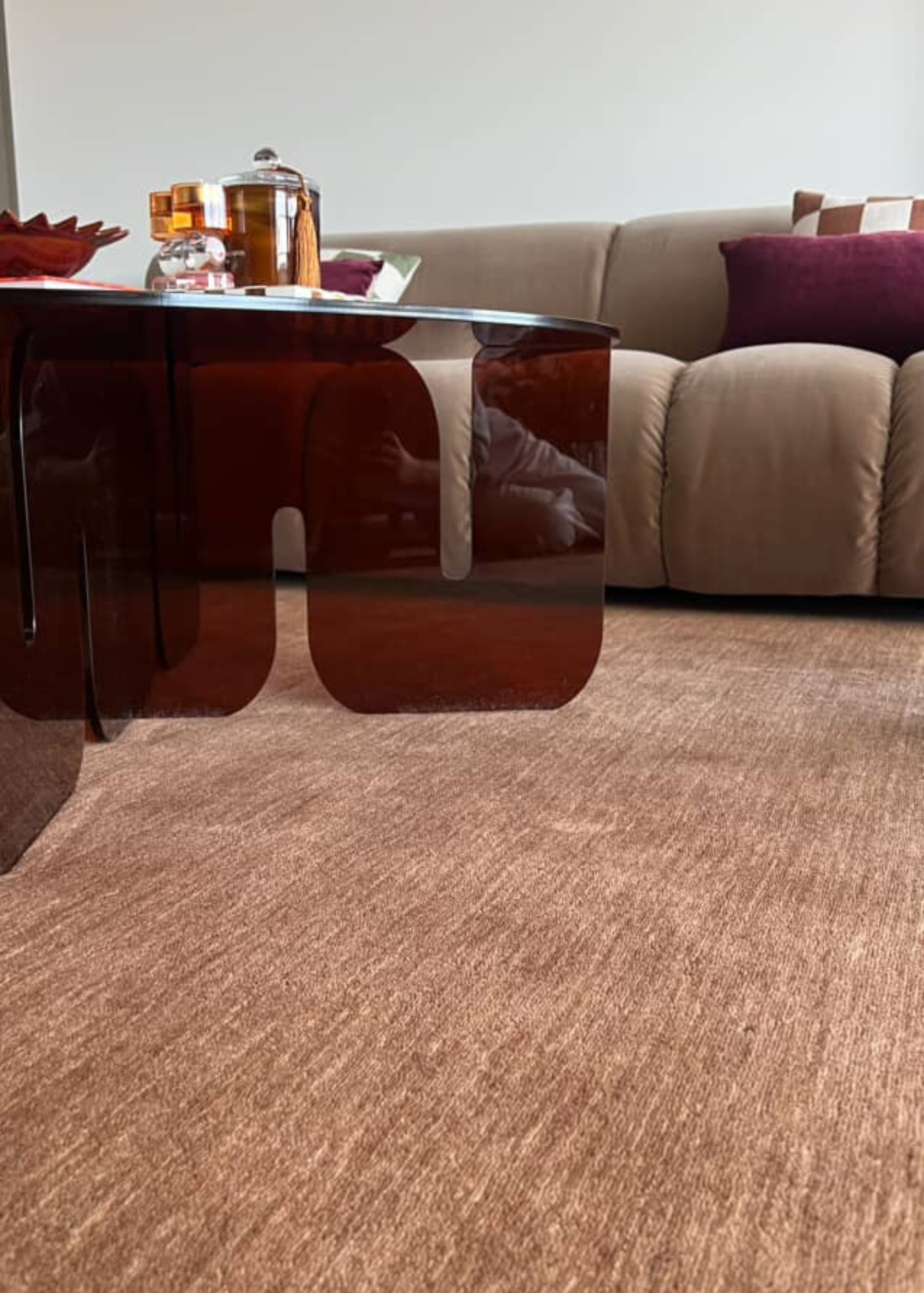 Living room with a burgundy glass coffee table, sofa, and decorative items on Wool Texture Teddy Brown Rug by Four Corners Rugs 